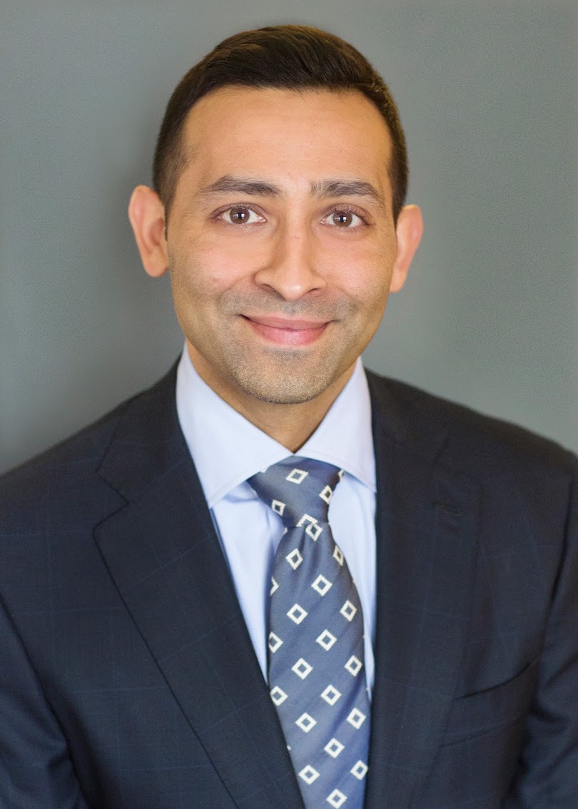 A confident professional man wearing a suit and tie, with a friendly smile.