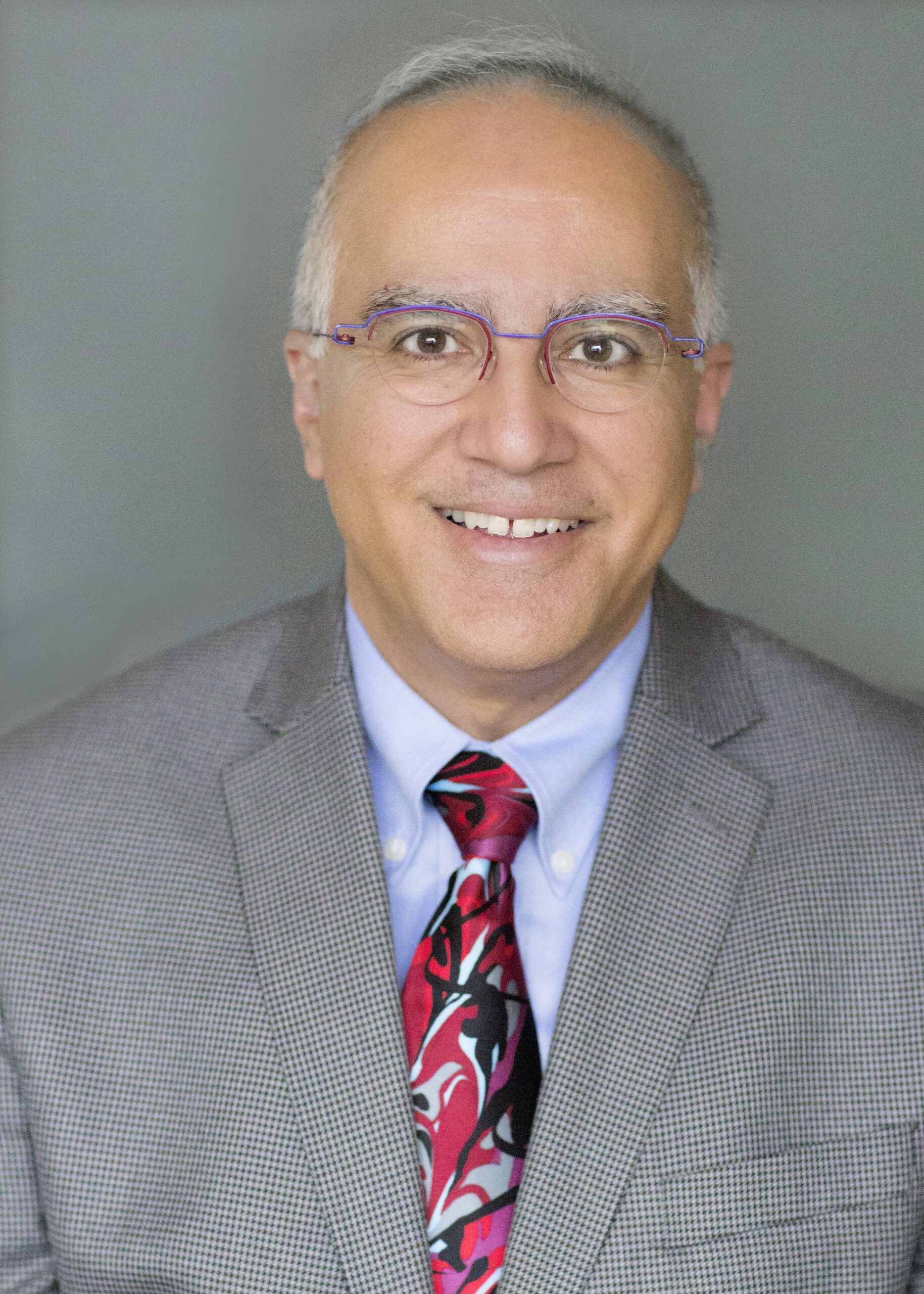 A confident professional in a suit and tie smiles for a formal portrait.