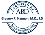 A blue and white circular seal with text indicating certification by the american board of dermatology, bearing the name gregory r. hannon, m.d., j.d.